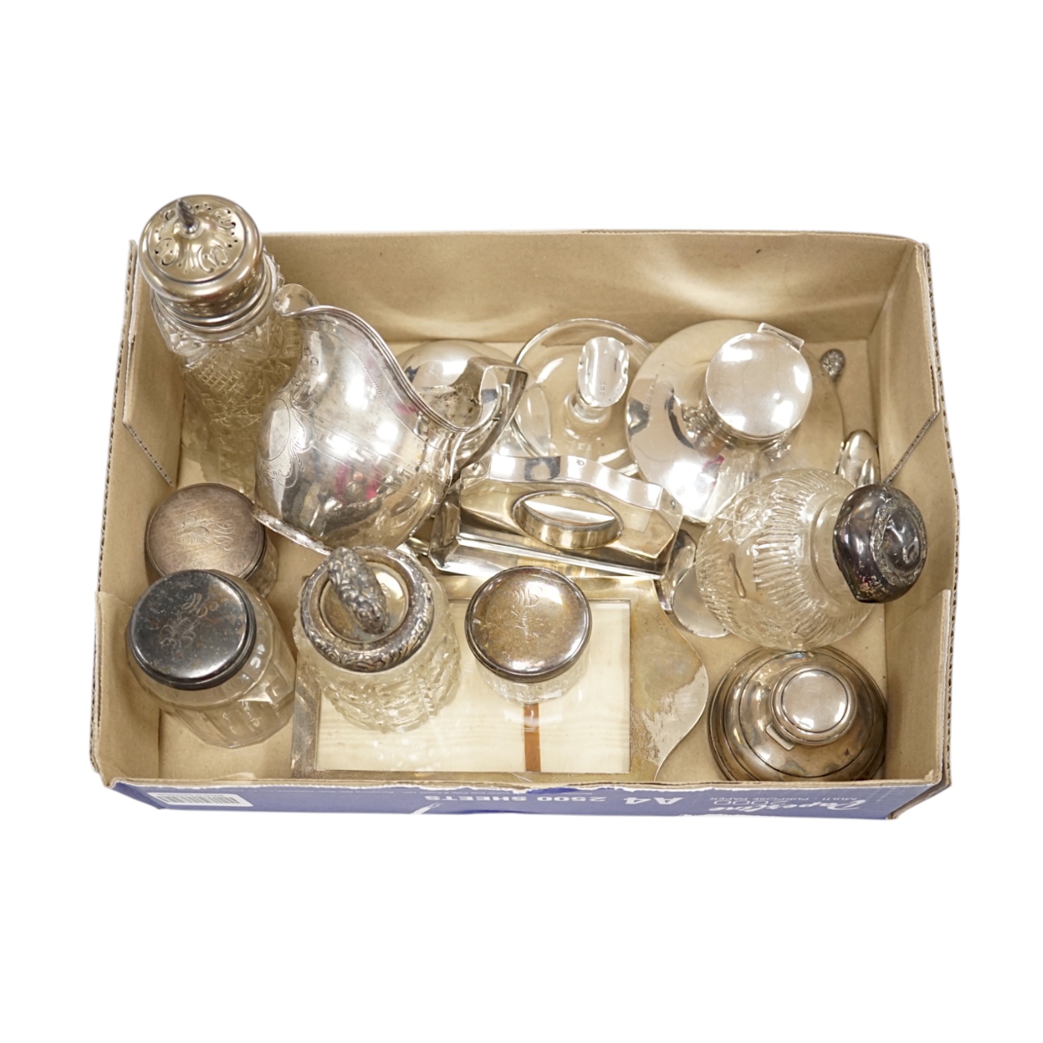 A quantity of assorted small silver including a George III cream jug(a.f.), three small capstan inkwells, a watch stand, photograph frame, mounted glass toilet jars etc. Condition - poor to fair